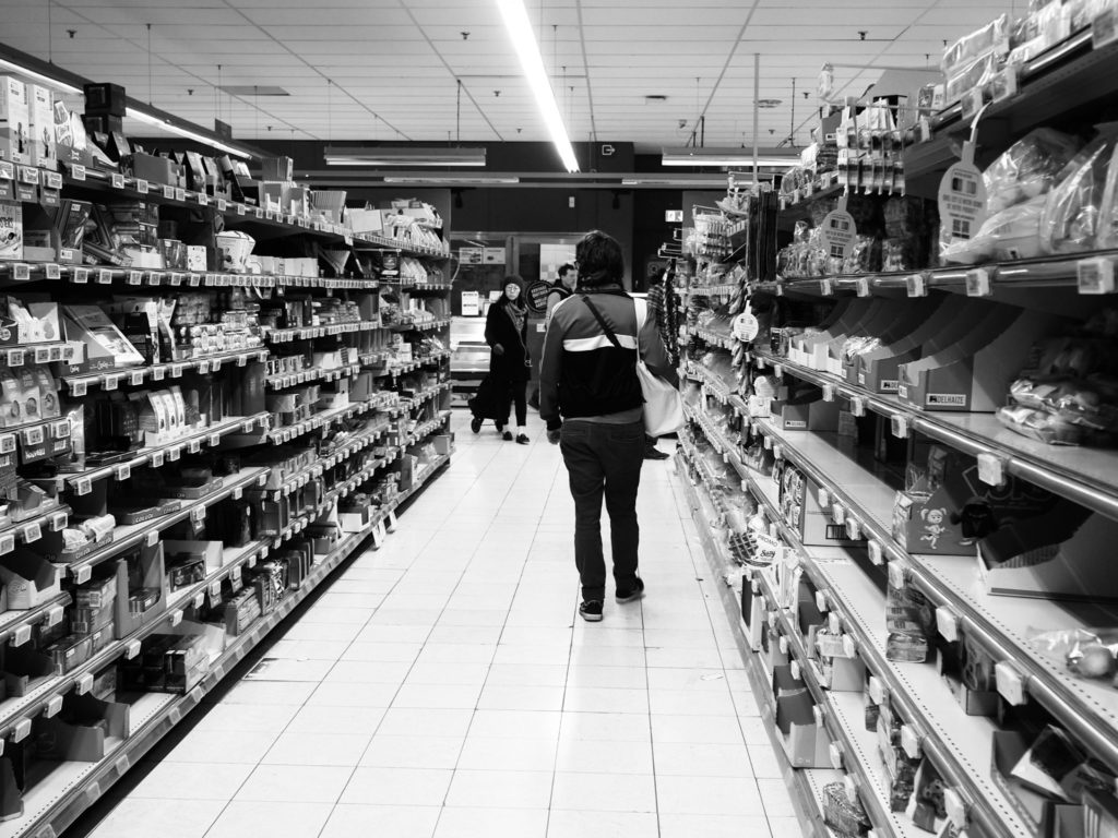 Une homme fait ses courses dans des rayons vides