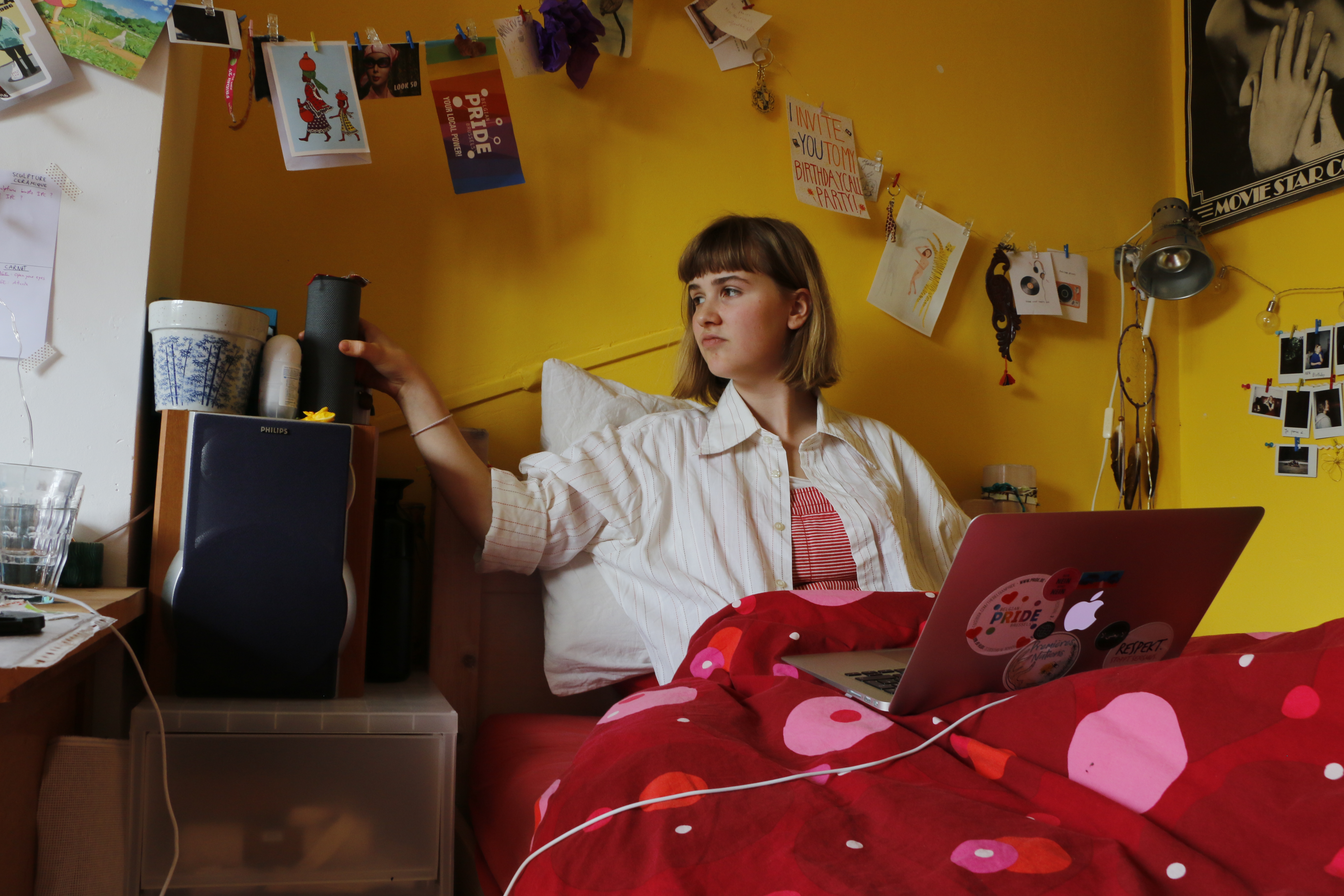 Une jeune fille regarde un concert assise dans son lit.
