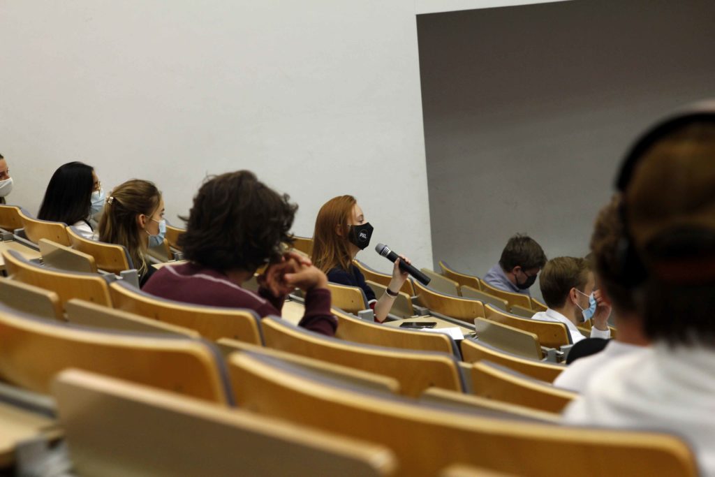 Étudiante assise dans un auditoire pose une question dans une micro
