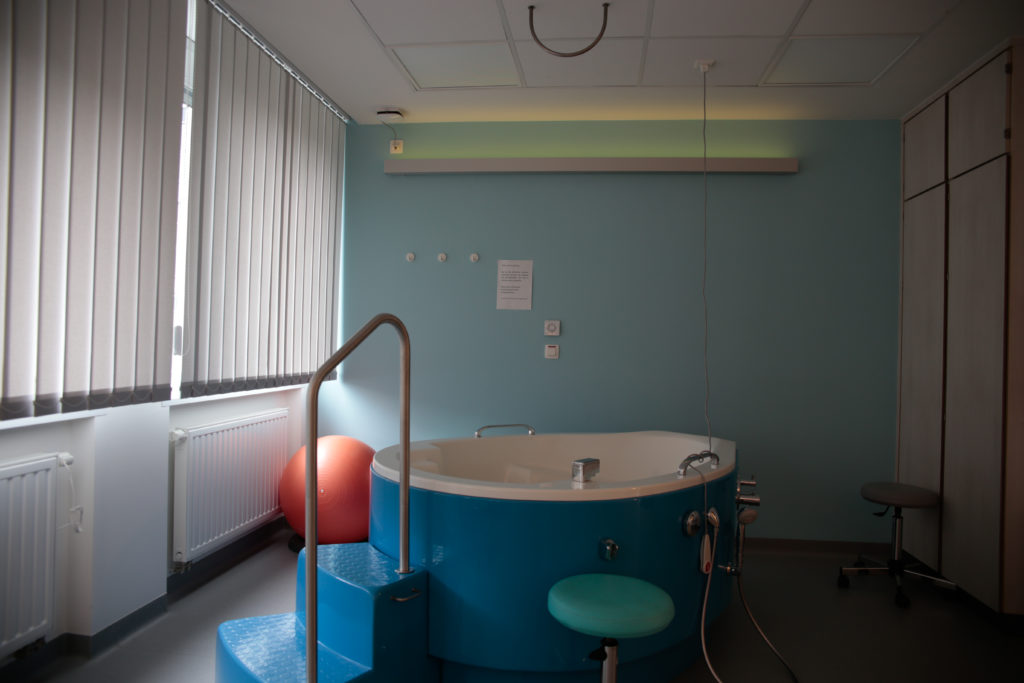 Salle de naissance avec un bain de dilatation bleu. 
