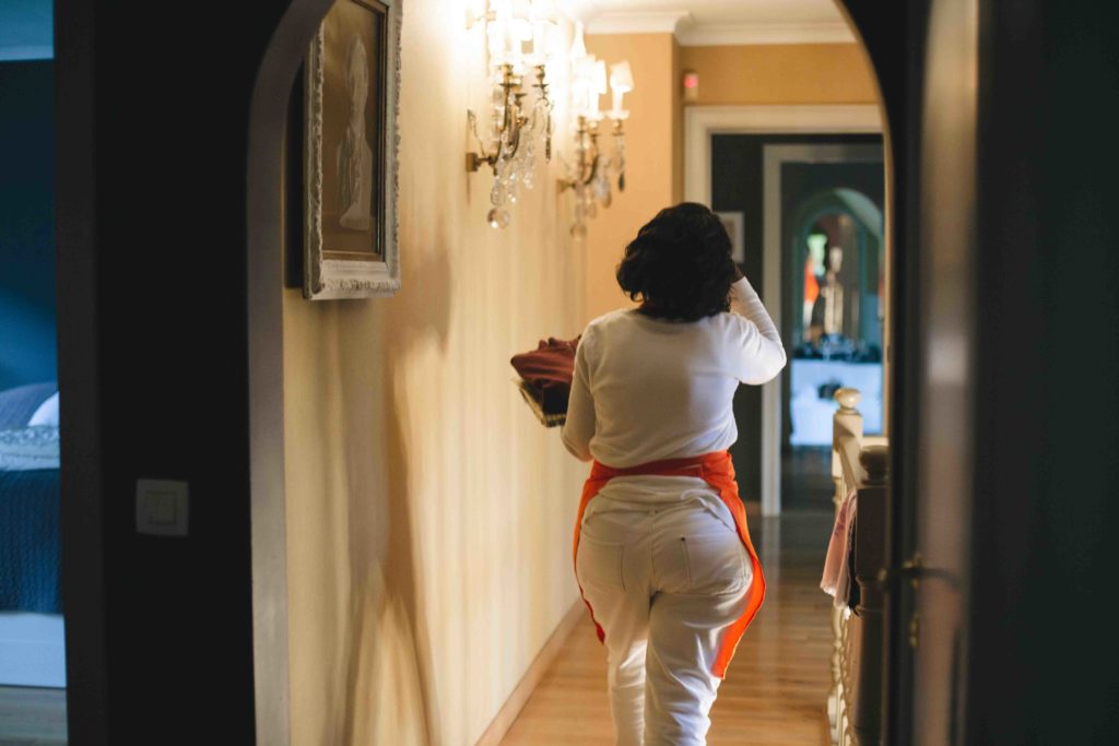 Mariam se déplace dans la grande maison pour aller ranger les chemises qu'elle vient de plier
