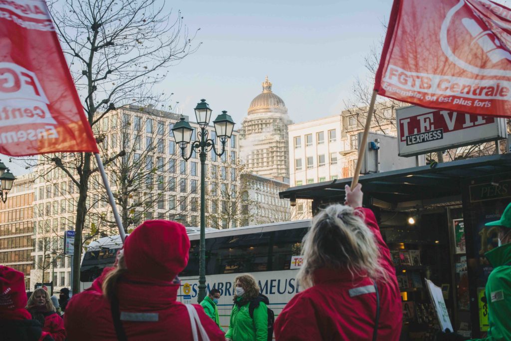 Deux déléguées syndicales agitent un drapeau de la FGTB, avec dans le fond le Palais de Justice